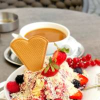 a dessert made of fruit, cream, and a heart-shaped cookie